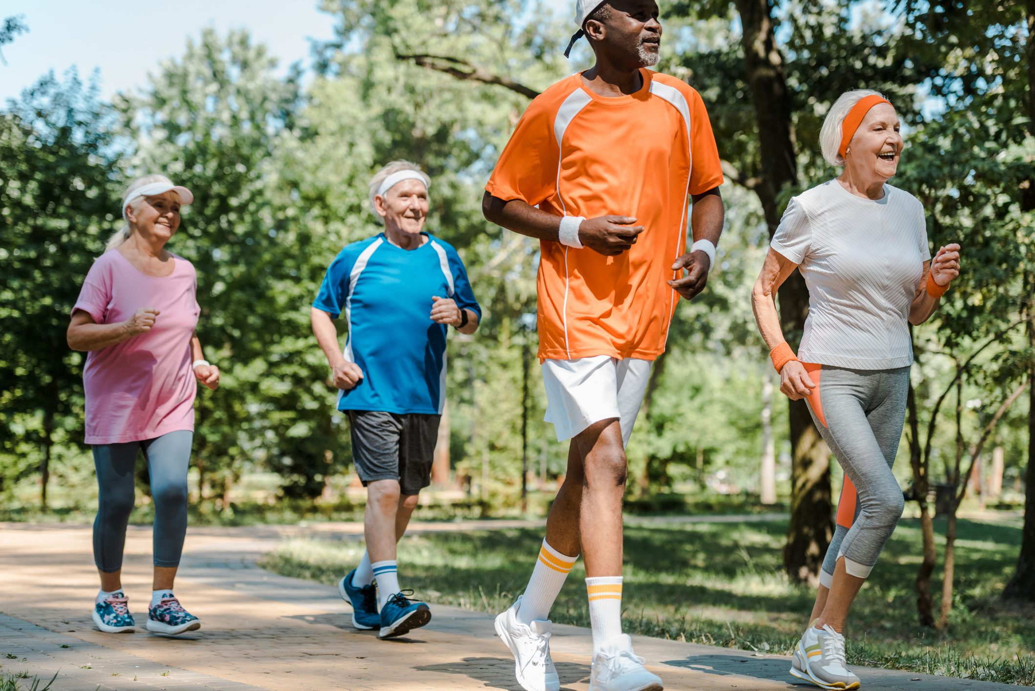 a group of multicultural older adults brisk walking or jogging on a sunny day
