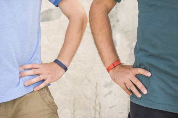 Image of two men's wrist wearing activity trackers like a Fit Bit