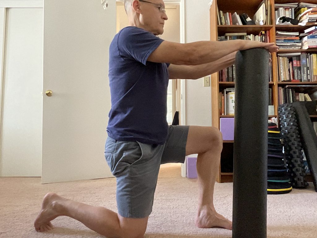 Image of person doing half-kneeling hip extension stretch with a foam roller in front