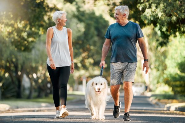 Older adult couple walking their dog outside