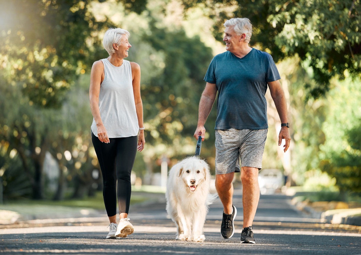 Older adult couple walking their dog outside