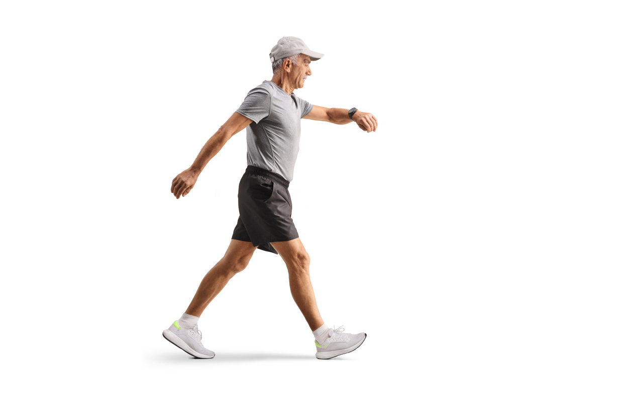 older adult man walking purposefully checking his watch