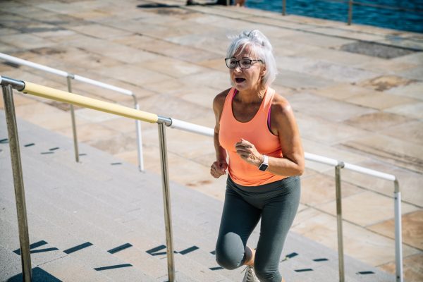 older adult woman running up outdoor stairs